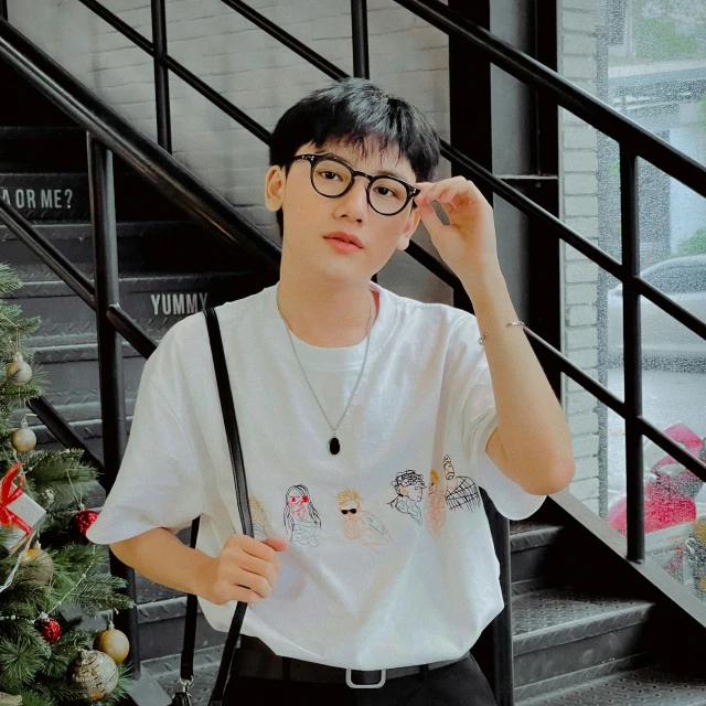 a young man standing in front of a christmas tree, an album cover, inspired by Chen Daofu, pexels contest winner, realism, short sleeves, eyeglasses, bt21, androgynous person