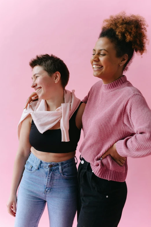 a couple of women standing next to each other, trending on pexels, ((pink)), non binary model, arm around her neck, playful and cheerful