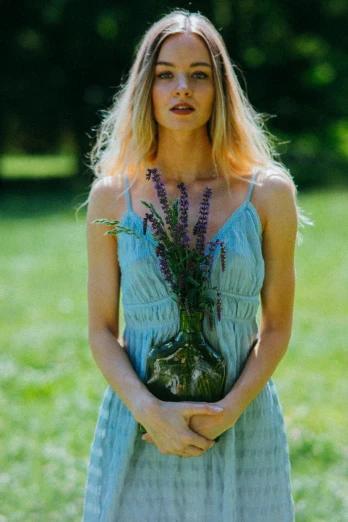 a woman in a blue dress holding a vase of flowers, inspired by Elsa Bleda, unsplash, young blonde woman, herbs, medium format, portait image