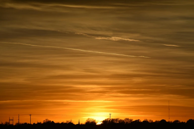 a plane flying in the sky at sunset, by Ian Fairweather, pexels contest winner, romanticism, yellow, landscape photo, brown, winter sun