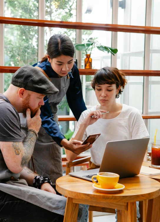 a group of people sitting around a table with a laptop