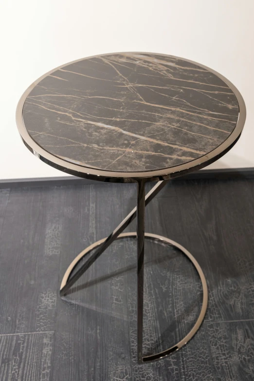 a table sitting on top of a hard wood floor, by Elizabeth Charleston, black marble and gold, round-cropped, made of brushed steel, cross