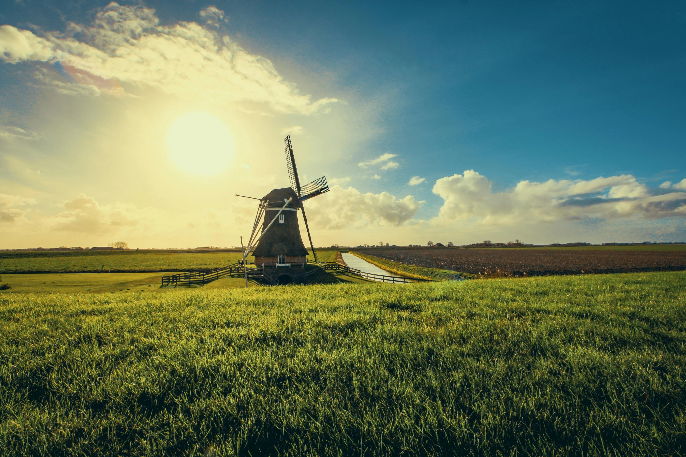 a windmill in the middle of a green field, pexels contest winner, dutch style, warmly lit, rustic, in the sun