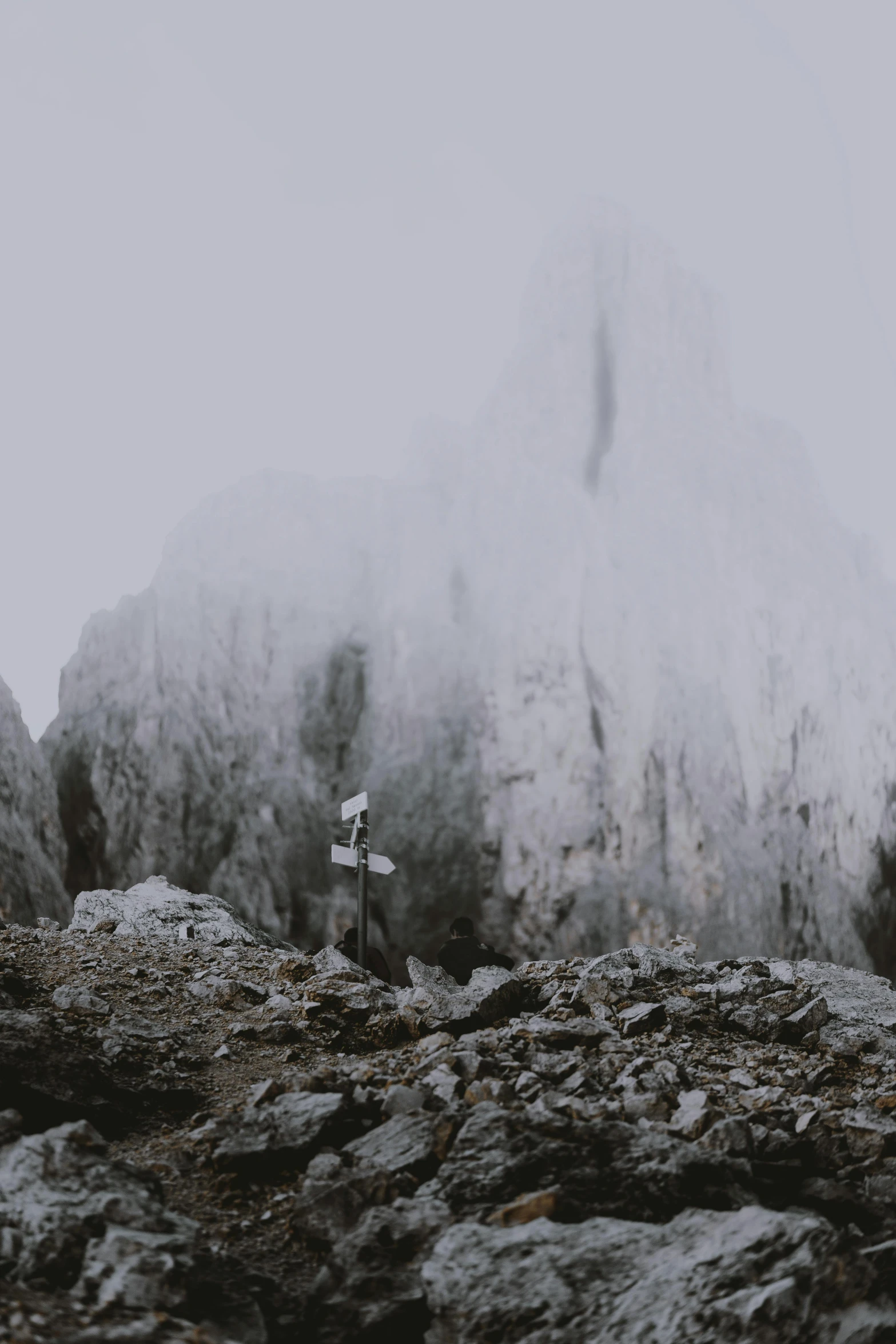 a group of people standing on top of a snow covered mountain, with jagged rocks & eerie, gray fog, rocks flying, unsplash 4k