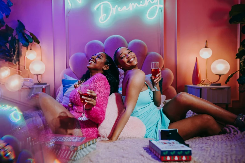 a couple of women sitting on top of a bed, an album cover, trending on pexels, happening, night clubs and neons, drinks, still image from tv series, dreamland