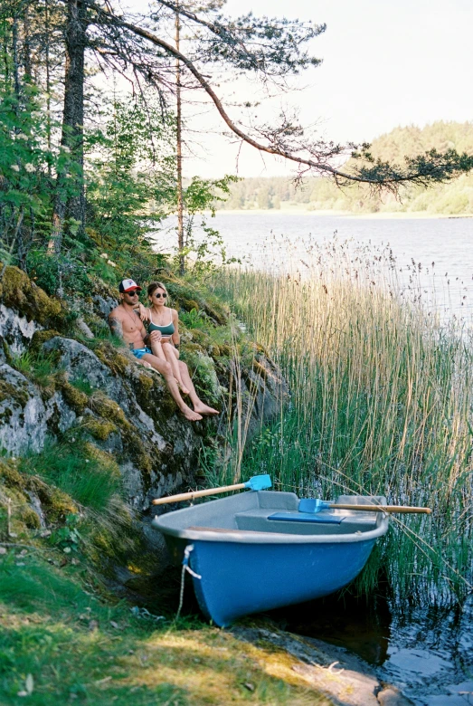 a man sitting on a rock next to a boat, swedish forest, 2 people, hot tub, male and female