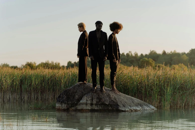 three men standing on a rock in the middle of a lake, an album cover, unsplash, purism, afrocentric mysticism, hammershøi, 3 actors on stage, black habit