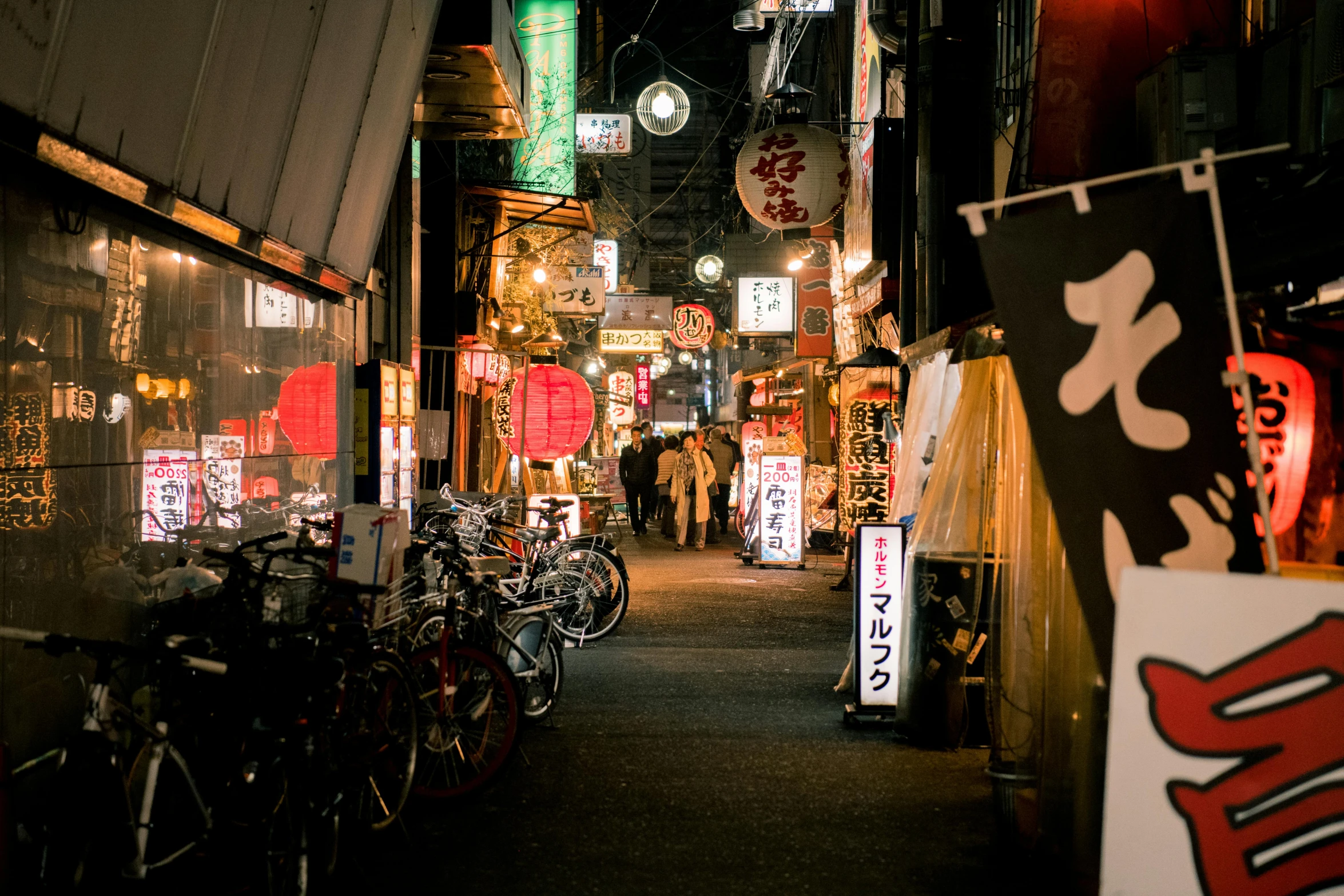 a group of bikes parked next to each other on a street, a photo, pexels contest winner, ukiyo-e, night life buildings, old shops, 🦩🪐🐞👩🏻🦳, people walking on street