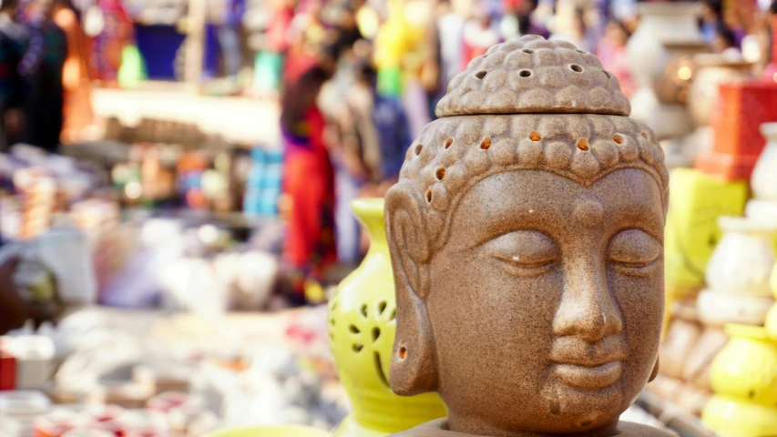 a close up of a statue in a market, trending on unsplash, hindu temple in background, the buddha, ceramics, coloured