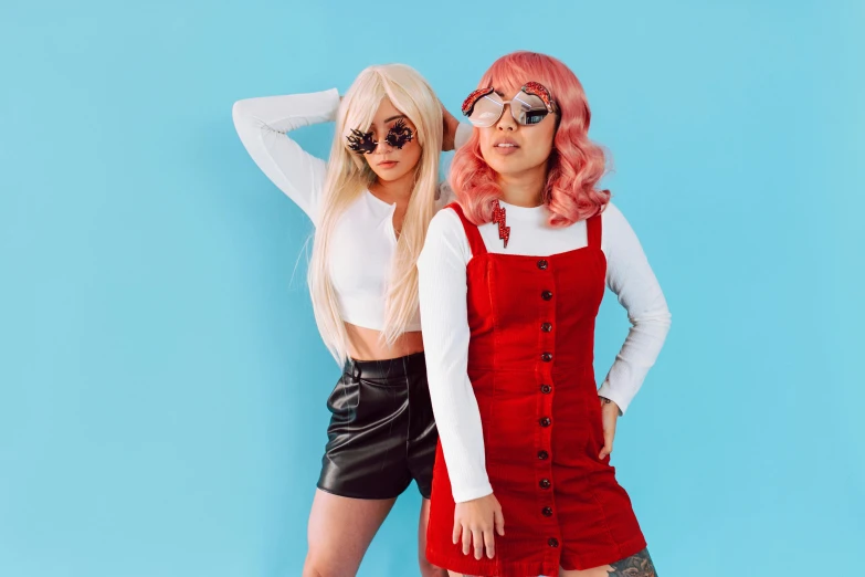 two women standing next to each other on a blue background, an album cover, trending on pexels, aestheticism, wearing red tainted glasses, overalls, wig, cosplayer