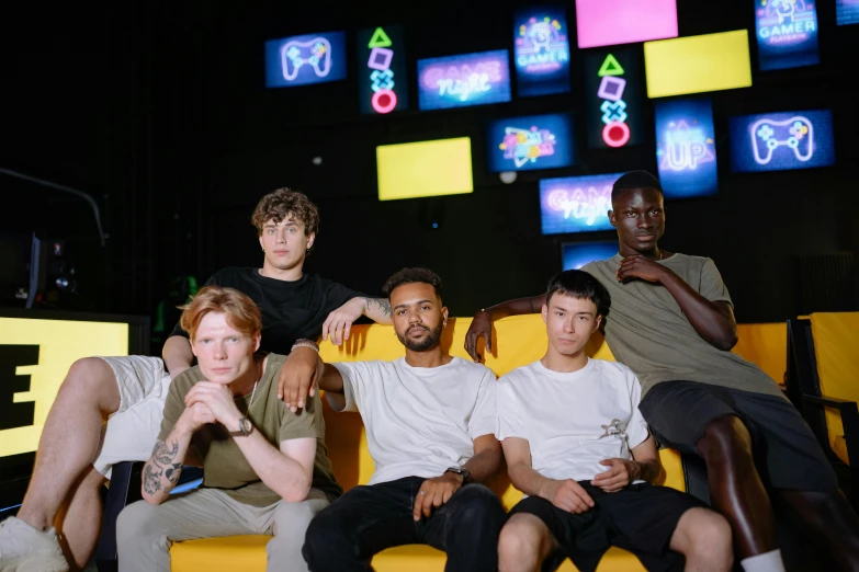 a group of young men sitting on top of a yellow couch, pexels contest winner, renaissance, neon lights in the background, led gaming, in group photograph, mix of ethnicities and genders