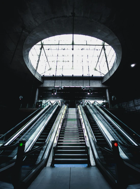 a couple of escalators sitting next to each other, an album cover, by Matthias Stom, unsplash contest winner, modernism, technological lights, train station, dark. no text, cinematic view from lower angle