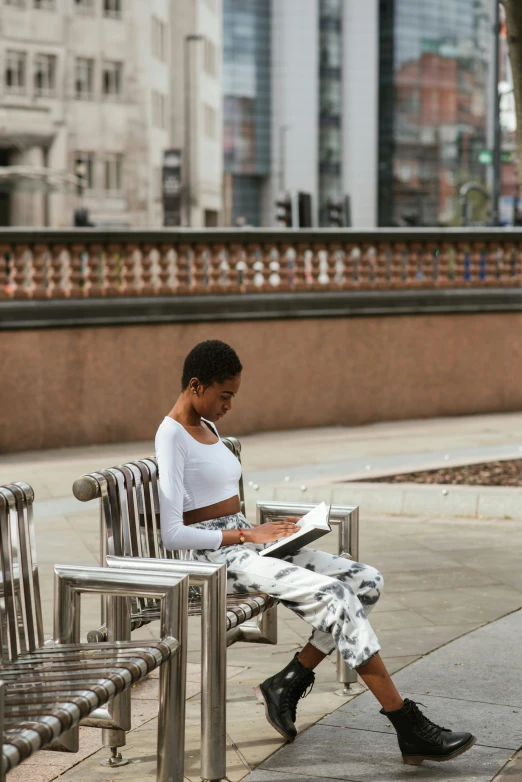 a woman sitting on a bench reading a book, visual art, manchester, black young woman, 2019 trending photo, in a square