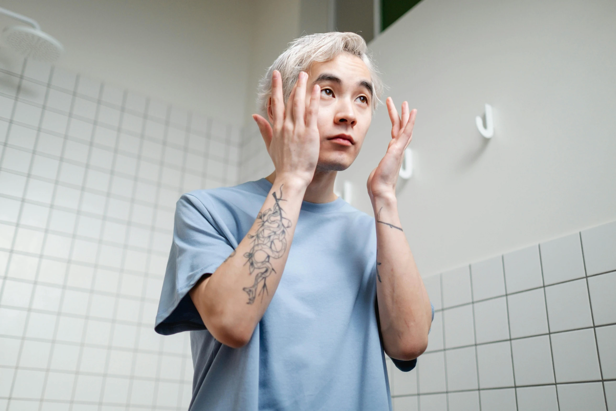 a man that is standing in front of a mirror, a tattoo, trending on pexels, hyperrealism, asian old skinny scientist, holding his hands up to his face, with blue hair, mrbeast