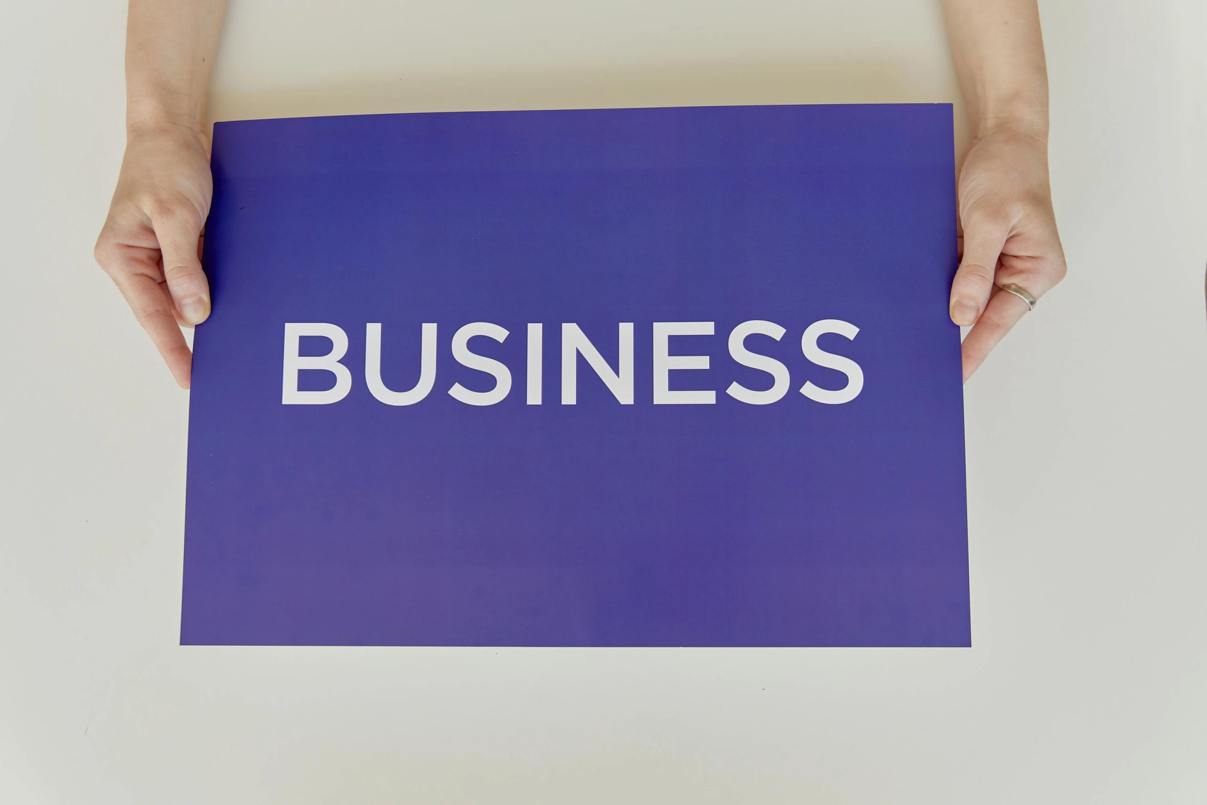 a person holding a sign that says business, a poster, unsplash, private press, purple themed, cut out of cardboard, minimal shading, hands not visible