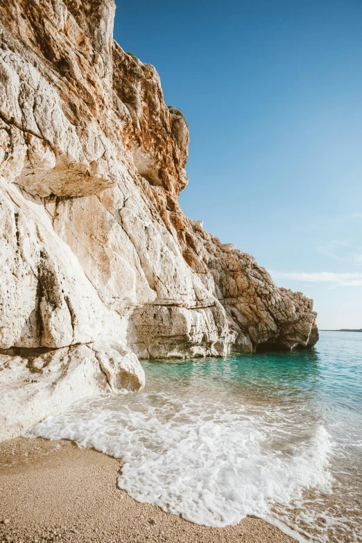 a man standing on top of a sandy beach next to the ocean, natural cave wall, greek elements, 2019 trending photo, slide show