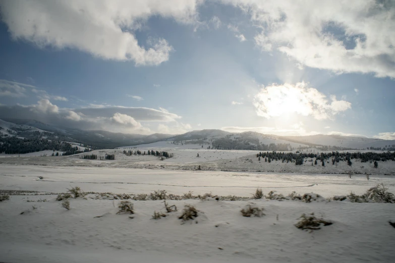 a snow covered field with mountains in the background, by Jessie Algie, pexels contest winner, hurufiyya, afternoon sun, white sky, big sky, conde nast traveler photo