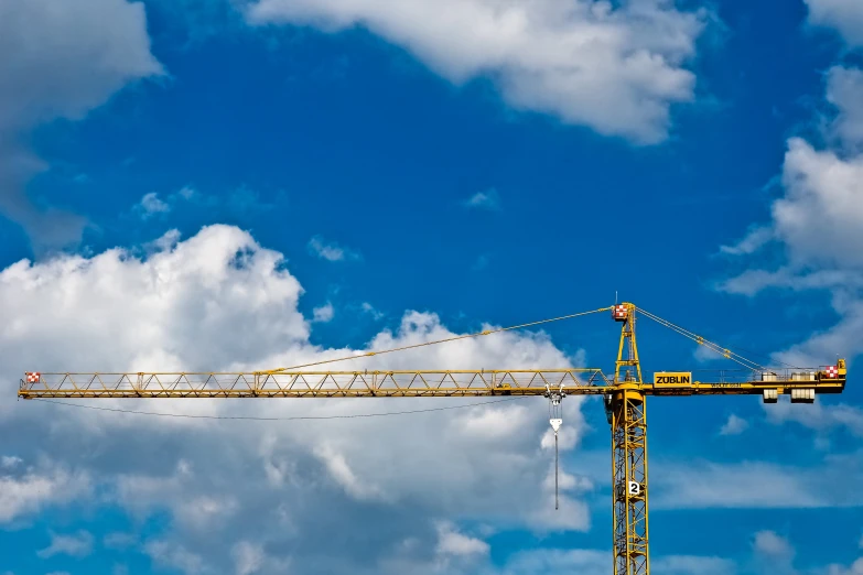 a crane sitting on top of a building under a blue sky, by Adam Marczyński, pexels contest winner, constructivism, commercial banner, avatar image, yellow and blue