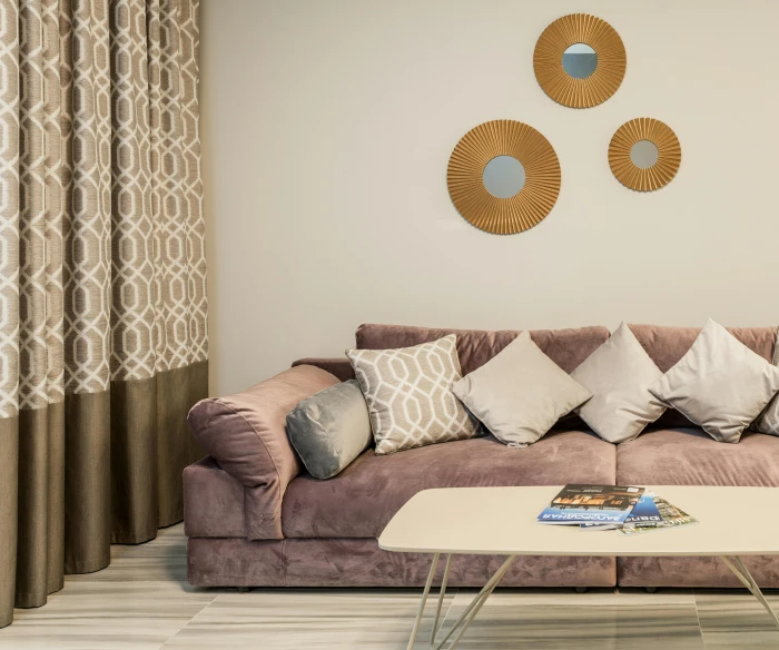 a living room with a couch and a coffee table, inspired by Alberto Morrocco, round mirror on the wall, gradient brown to silver, 3 - piece, decoration