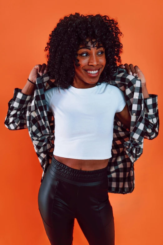 a woman posing in front of an orange background, by Washington Allston, trending on pexels, cropped shirt with jacket, flannel, black on white background, sza