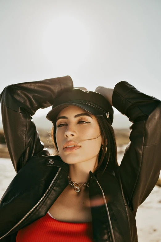 a woman in a red top and black leather jacket, an album cover, inspired by Elsa Bleda, trending on pexels, she is wearing a hat, sunny day time, charli xcx, leather jewelry