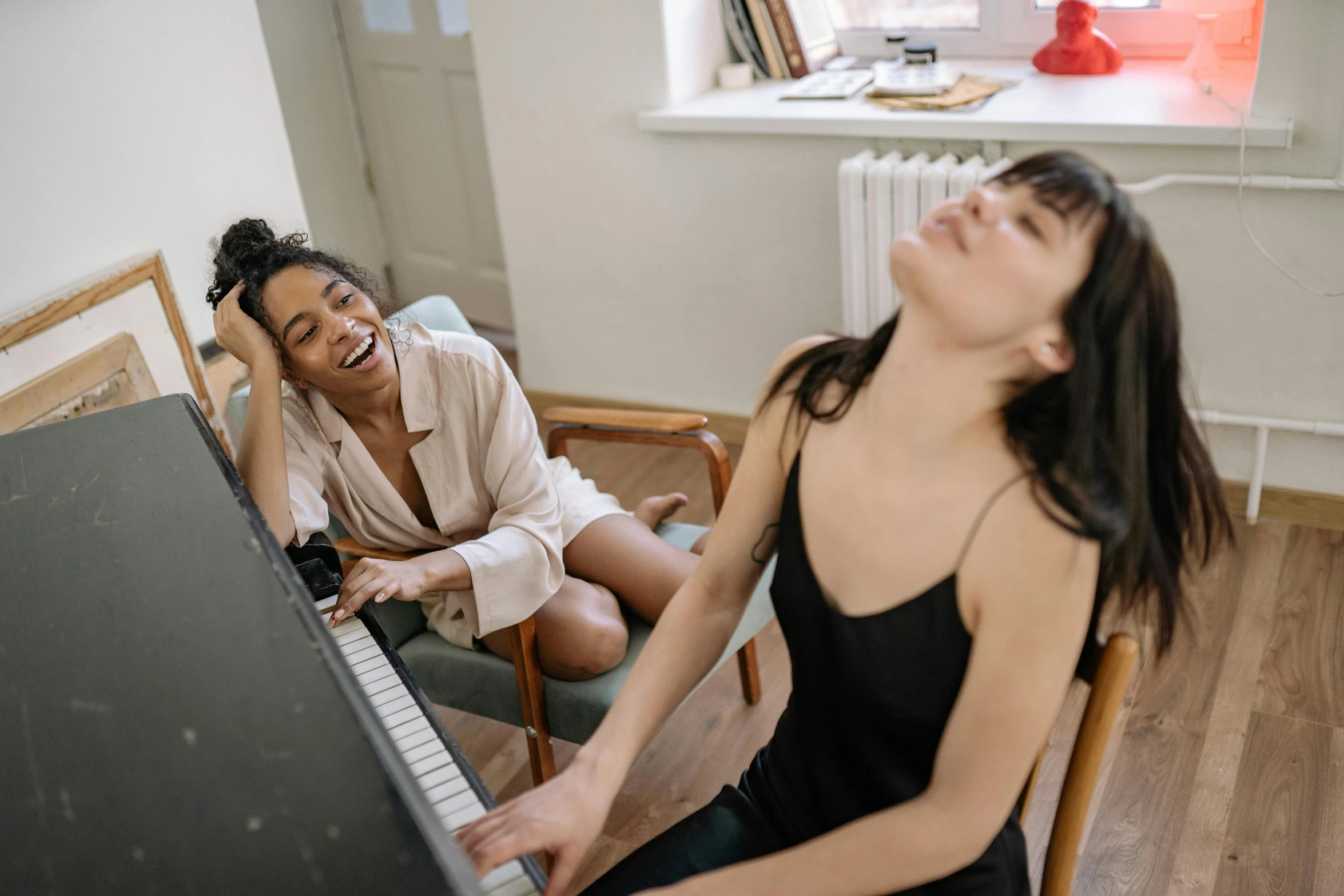 a woman sitting on a chair in front of a piano, trending on pexels, happening, two buddies sitting in a room, head bent back in laughter, two girls, sleepy feeling