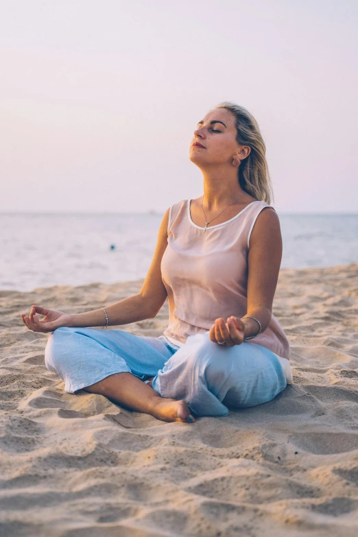 a woman sitting on top of a sandy beach, trending on pexels, renaissance, meditating in lotus position, blonde women, pink, smoking with squat down pose