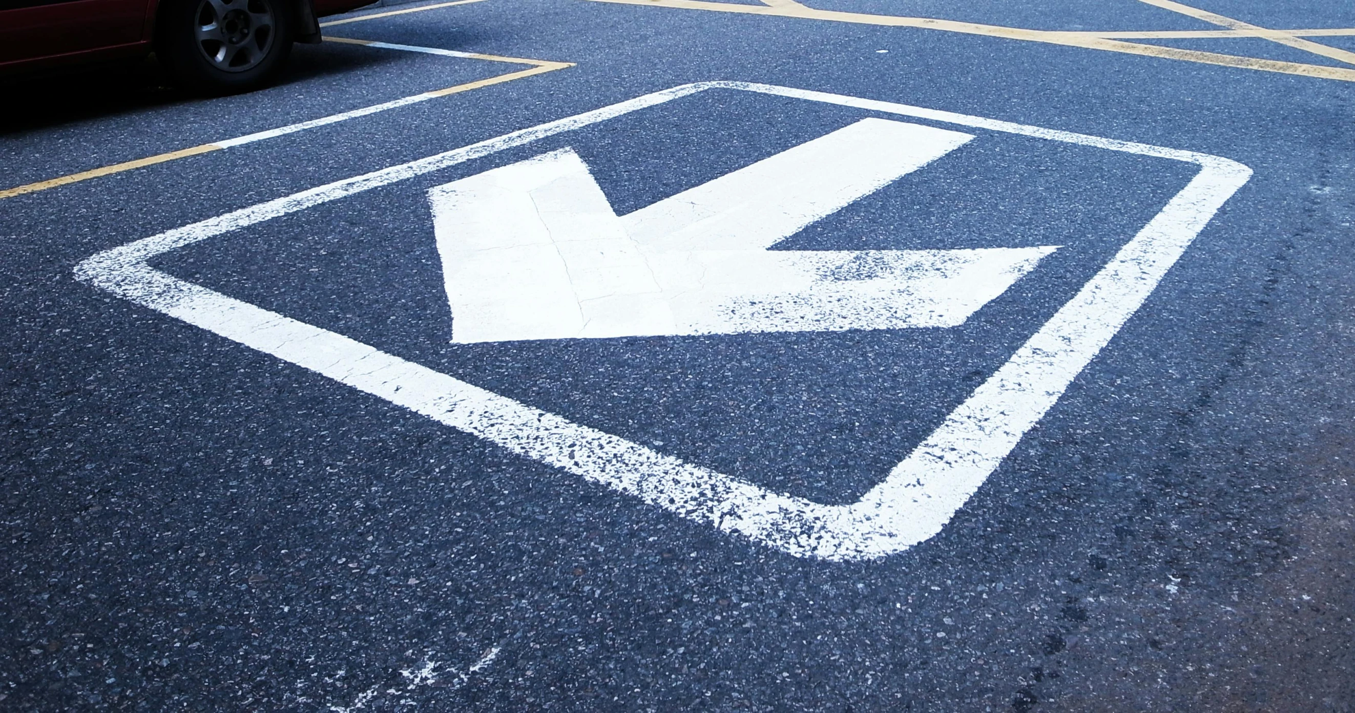 a white arrow painted in the middle of a parking lot, unsplash, auto-destructive art, square, pictogram, head down, royal commission