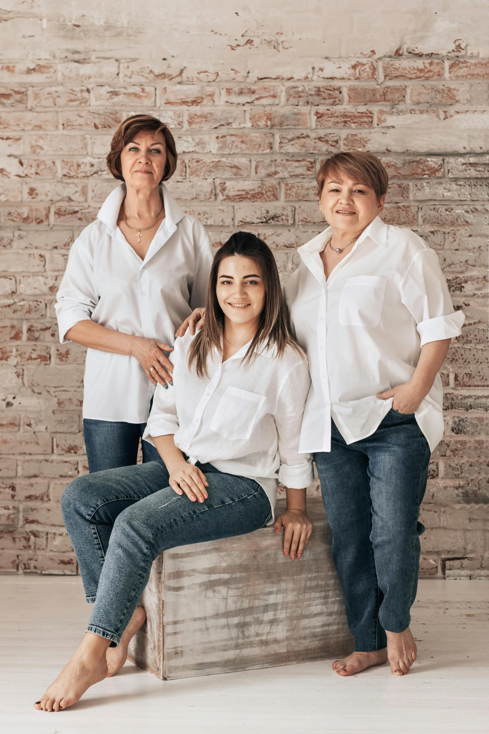 three women sitting next to each other in front of a brick wall, white shirt and jeans, portrait of morana, your mom, portrait image