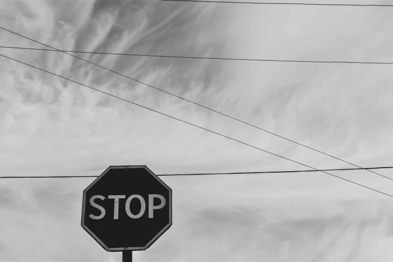 a black and white photo of a stop sign, a black and white photo, unsplash, postminimalism, tangled overhead wires, instagram post, skies, photorealistic ”