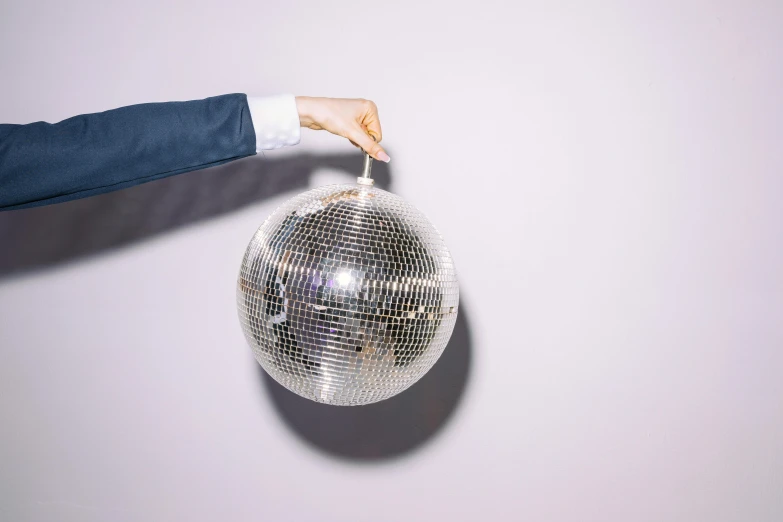 a person holding a disco ball in their hand, an album cover, trending on pexels, arabesque, clemens ascher, silver，ivory, (night), glossy white metal