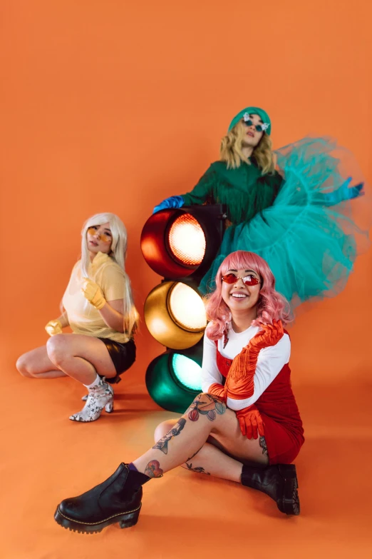 a group of women sitting next to each other, an album cover, trending on pexels, kitsch movement, orange and cyan lighting, bright hair, full body with costume, doing a sassy pose