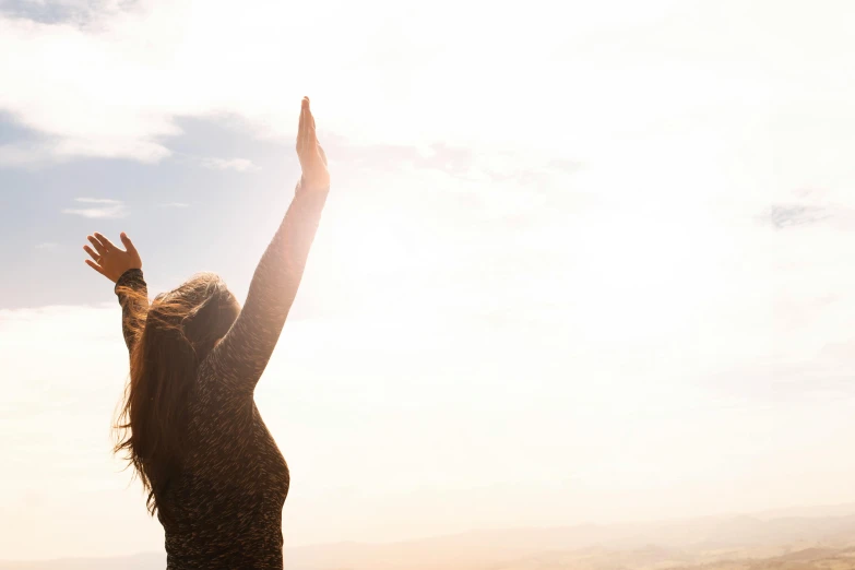 a woman standing on top of a hill with her arms in the air, pexels contest winner, figuration libre, recovering from pain, sun lit, kundalini energy, plain background
