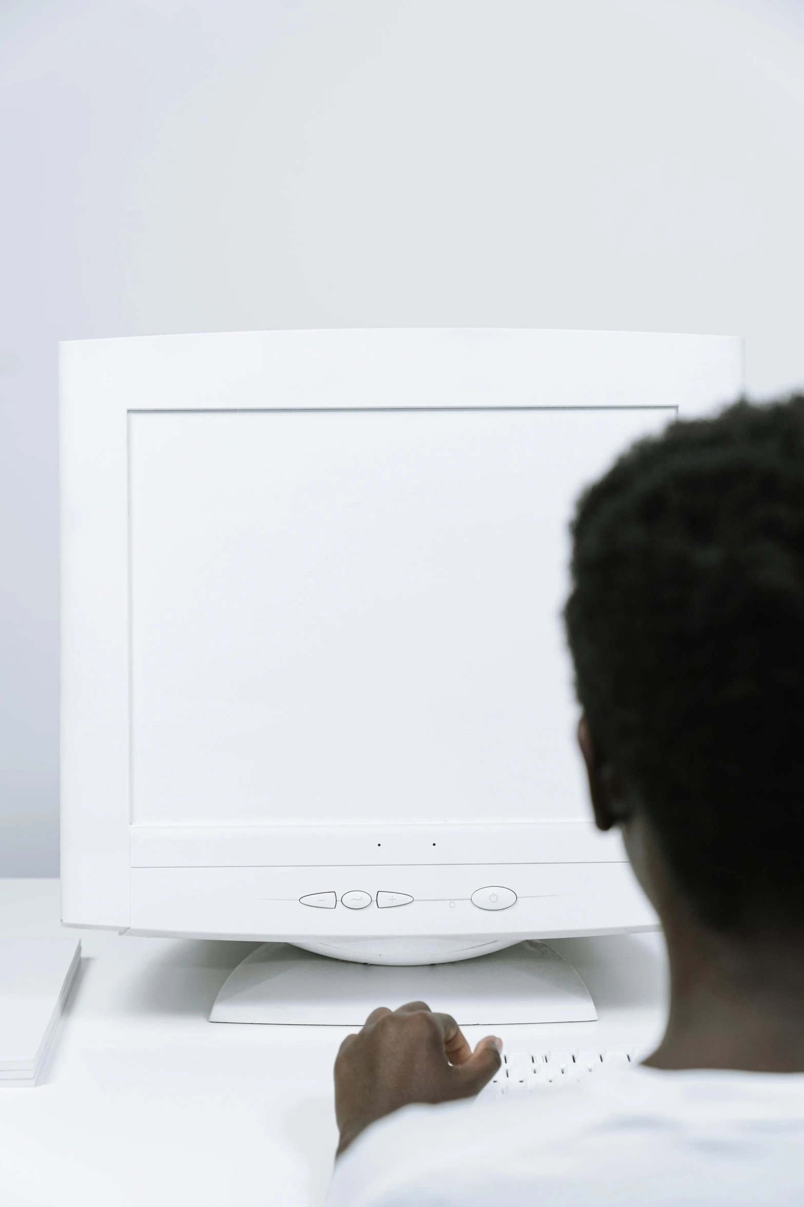 a person sitting in front of a computer on a desk, inspired by Carrie Mae Weems, pexels, computer art, crt television, looking from behind, high key, man?