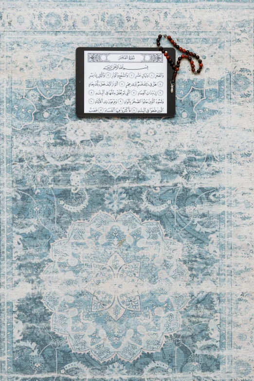 a tablet computer sitting on top of a blue rug, poster art, inspired by Maryam Hashemi, hurufiyya, 2 5 6 x 2 5 6, sheet music, prayer, wall paper