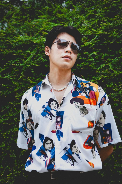 a man wearing sunglasses standing in front of a bush, an album cover, inspired by Eiichiro Oda, unsplash, neo-dada, button - up shirt, elvis, declan mckenna, with hawaiian shirt