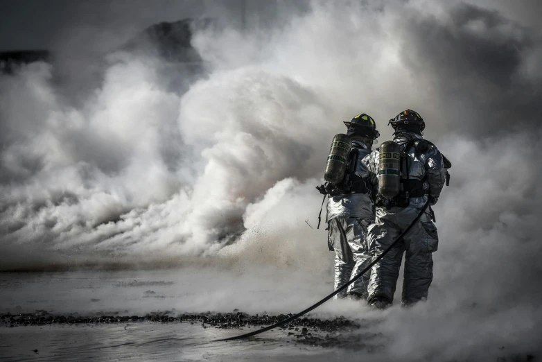 a couple of men standing next to each other on top of a field, by Adam Marczyński, pexels contest winner, firefighting gear, dry ice, closeup photograph, gpu fire