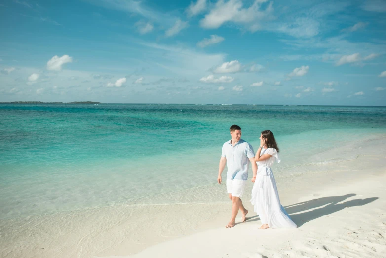 a man and a woman walking on a beach, inspired by Edwin Georgi, pexels contest winner, hurufiyya, maldives in background, white and teal garment, crystal clear blue water, romantic