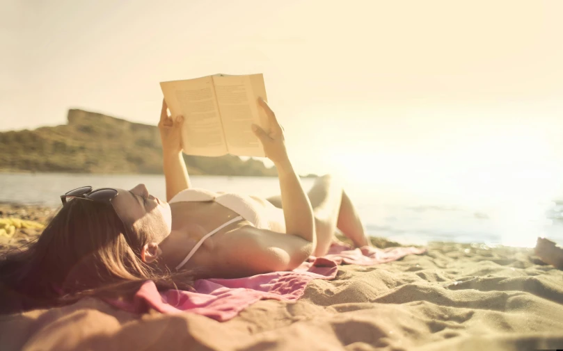 a woman laying on a beach reading a book, pexels contest winner, sun overhead, sunburn, profile image, reading for a party