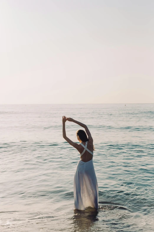 a woman in a white dress standing in the ocean, unsplash contest winner, arabesque, meditating pose, late summer evening, modern dance aesthetic, instagram post