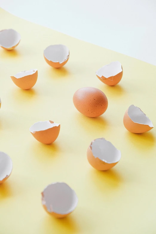 a group of eggs sitting on top of a yellow surface, torn edges, laura watson, exploring, repeating pattern