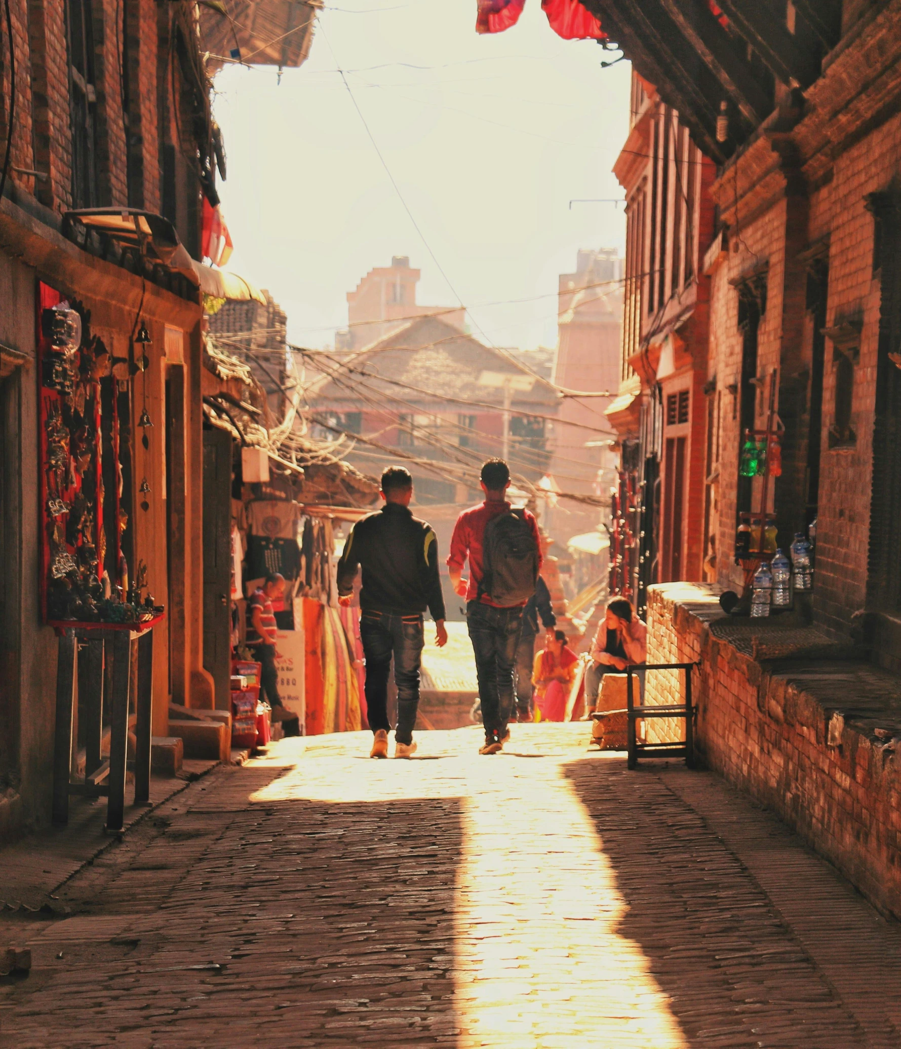 a couple of people that are walking down a street, by Joseph Severn, pexels contest winner, nepali architecture buildings, warm sunlight shining in, a quaint, bright ”