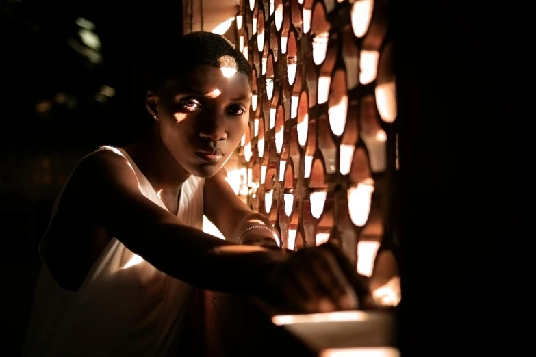 a close up of a person near a window, inspired by Gordon Parks, pexels contest winner, afrofuturism, lit with candles, in front of a carved screen, summer lighting, single light