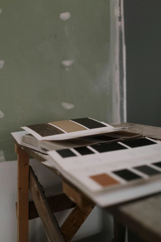 a piece of paper sitting on top of a wooden table, a detailed painting, inspired by Brice Marden, unsplash, color field, tiny room with dirty wall tiles, color chart, black and brown, shot from cinematic
