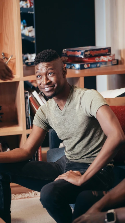 a man sitting on a couch holding a baseball bat, by Amos Ferguson, trending on reddit, hurufiyya, smiling male, on a desk, man is with black skin, lgbtq