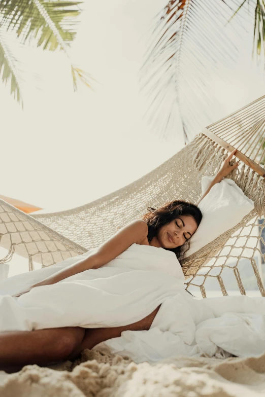 a woman laying in a hammock on the beach, a portrait, pexels contest winner, renaissance, white sheets, relaxed. gold background, resort, subtle detailing