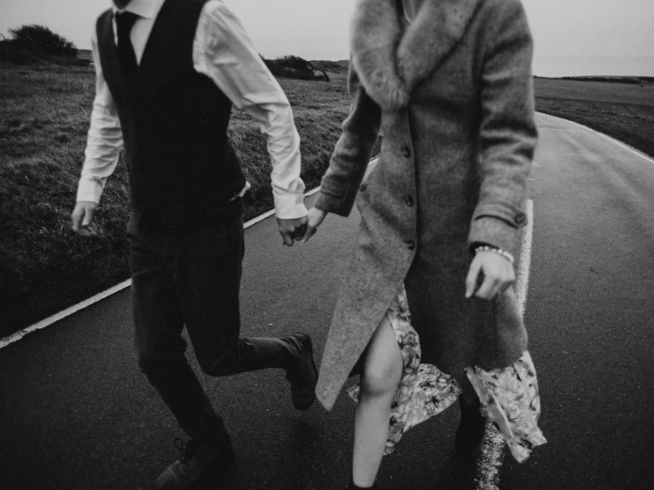 a man and a woman walking down a road, a black and white photo, by Emma Andijewska, pexels, renaissance, background image, spinning hands and feet, retro vintage and romanticism, snapchat photo