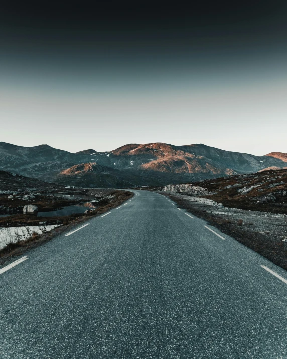 an empty road with mountains in the background, an album cover, trending on unsplash, norway, thumbnail, multiple stories, late evening