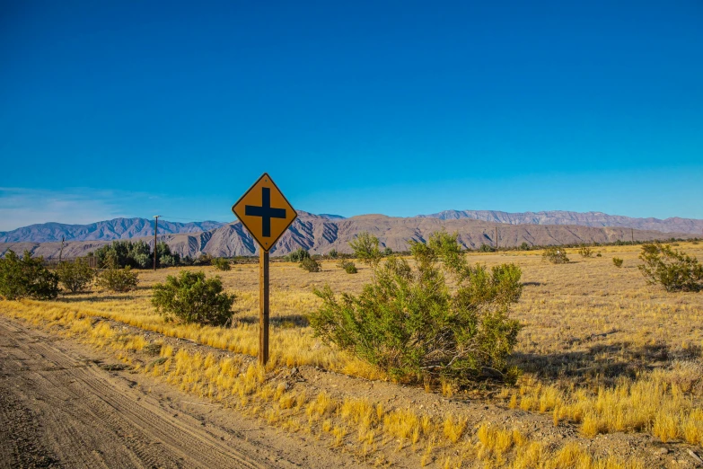 a road sign on the side of a dirt road, unsplash, precisionism, square, palm springs, cross, panoramic