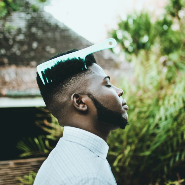 a man with a comb on his head, trending on pexels, afrofuturism, jaylen brown, teal color graded, beautiful surroundings, 5 feet away